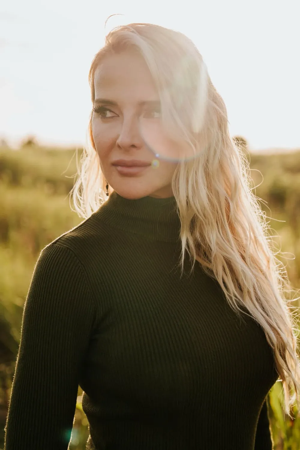 Julia outdoors in late light, wearing a black high-necked top.